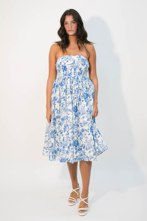Woman wearing a blue floral strapless dress against a white background