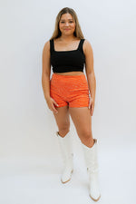 orange and black game day outfit with white boots and orange statement shorts bottoms